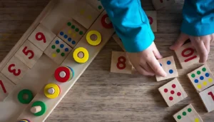 Home 25 A child is learning to count with wooden number blocks and dice.